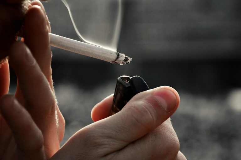 Detailed image of hands holding a cigarette and lighter, emphasizing smoking habit.